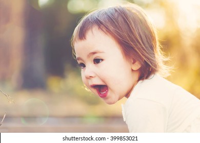 Happy Toddler Girl Playing Outside At Sunset