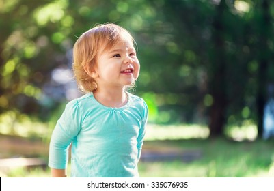 Happy Toddler Girl Smiling Outside On A Sunny Afternoon