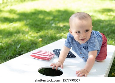 Happy Toddler Playing On Corn Hole Game Board In Backyard In Summer