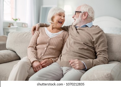 Happy together. Joyful elderly couple smiling to each other while being in a great mood