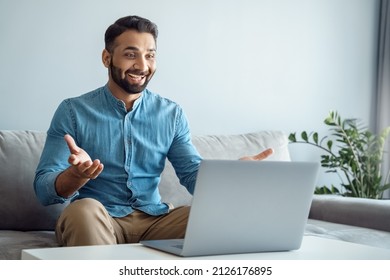 Happy Toothy Smiling Indian Man Glad To See Best Friend Making Online Video Call. Young Arab Guy Talking On Video Conference At Modern Home Office Using Remote Distant Online Communication Technology