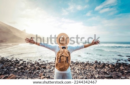 Happy tourist with backpack enjoying freedom raising arms up - Wellbeing, journey and tourism concept