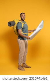Happy tourist with backpack and map on yellow background - Shutterstock ID 2310741461