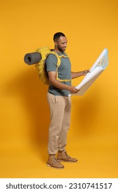 Happy tourist with backpack and map on yellow background - Shutterstock ID 2310741517