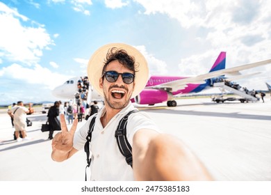 Feliz embarque de turistas en un avión en el aeropuerto - Joven guapo tomando una foto selfie frente al avión - Vacaciones de verano y concepto de estilo de vida de transporte