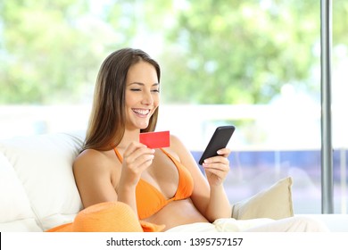 Happy tourist booking online with phone and credit card in an apartment on summer vacation - Powered by Shutterstock