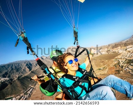 Happy tourist doing paragliding sport activity in outdoor leisure active lifestyle. Cheerful adult woman doing selfie picture flying on a paraglyde in summer holiday vacation. Freedom joyful people