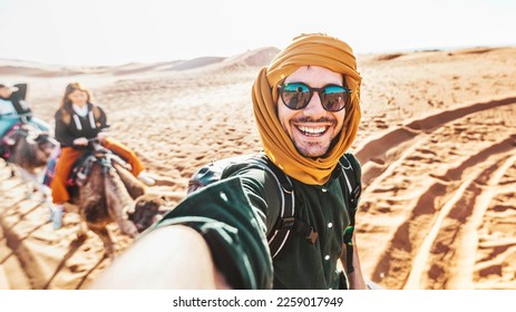 Happy tourist having fun enjoying group camel ride tour in the desert - Travel, life style, vacation activities and adventure concept