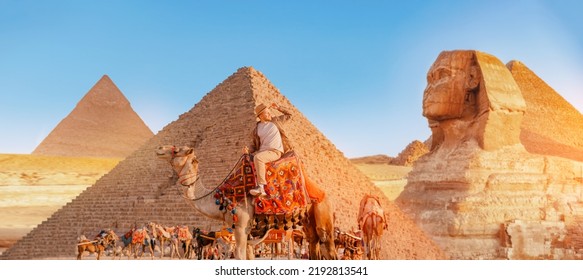 Happy Tourist man with hat riding on camel background pyramid of Egyptian Giza, sunset Cairo, Egypt. - Shutterstock ID 2192813541