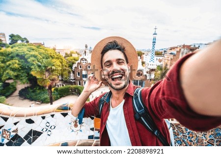 Happy tourist take selfie self-portrait with smartphone in Park Guell, Barcelona, Spain - Smiling man on vacation looking at camera - Holidays and travel concept