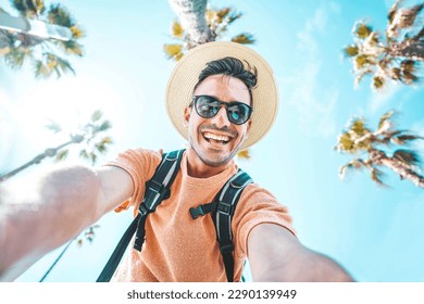 Happy tourist taking self portrait outside with cellphone on summer vacation - Handsome young man laughing at camera enjoying summertime day out - Tourism, traveler life style and technology concept - Powered by Shutterstock