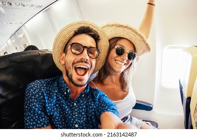 Happy tourist taking selfie inside airplane - Cheerful couple on summer vacation - Passengers boarding on plane - Holidays and transportation concept - Shutterstock ID 2163142487