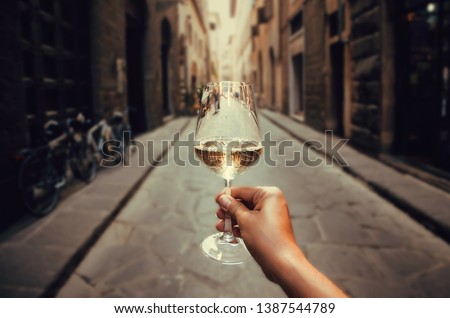 Happy tourist walking on narrow streets with white wine glass in hand. Enjoying life concept.