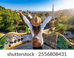 A happy tourist woman enjoys the view of the popular Park Güell in Barcelona, Spain, on a sunny day