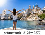 A happy tourist woman on summer vacation looks at the famous Vaporia district at Ermoupoli, Syros island, Cyclades, Greece