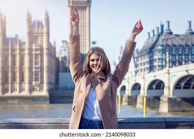 A happy tourist woman stands in front of the Big Ben clocktower at Westminster, London