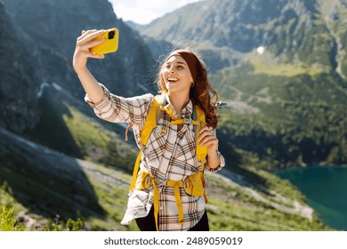 Happy tourist woman taking picture outdoors for memories, sharing photo of landscape nature background enjoying vacation holiday travel adventure. Selfie time. - Powered by Shutterstock