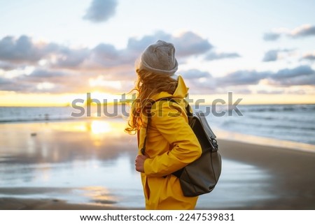 Happy tourist in a yellow jacket enjoying sea landscape at sunset. Travelling, lifestyle, adventure.