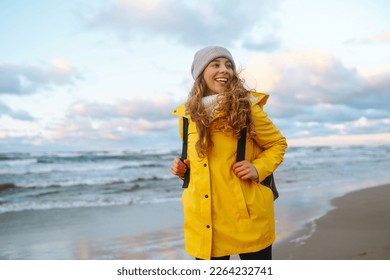 Happy tourist in a yellow jacket standing and looking on sea. Lifestyle, travel, tourism, nature, active life. - Powered by Shutterstock