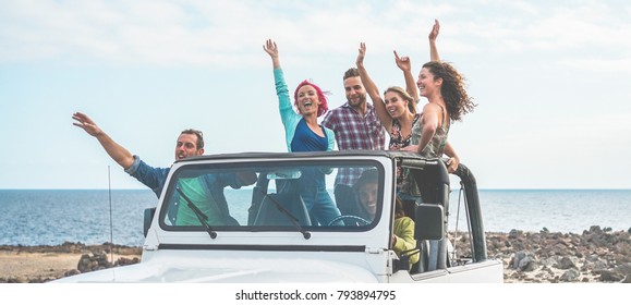 Happy tourists friends doing excursion in desert on convertible jeep car - Young people having fun traveling together - Friendship, youth lifestyle and vacation concept - Focus on guys with hands up - Powered by Shutterstock