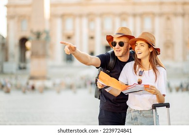 Happy tourists looking at a map. Couple of tourists on vacation in Rome, Italy. A young couple of tourists choose a hotel. Honeymoon. Satisfied tourists looking for a direction on a map. 