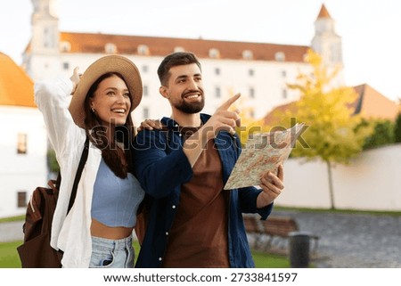 Happy tourists smiling, using map while looking around the city on sunny day, planning route to landmarks, free space