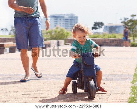 Happy, toy and motorbike with child and father playing in park for bonding, laugh and fun. Smile, happiness and energy with man and young boy riding on scooter for playful, youth and summer