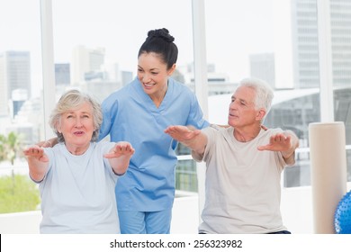 Happy trainer assisting senior couple to exercise in gym - Powered by Shutterstock