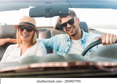 Happy to travel together. Joyful young couple smiling while riding in their convertible 