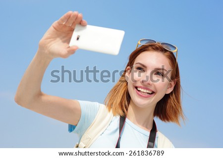 Happy travel woman take a selfie picture by smart phone with sky background, caucasian beauty