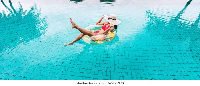 Happy traveler asian woman with bikini relax on big pink flamingo pool float in swimming pool at Thailand, summer travel vacation concept