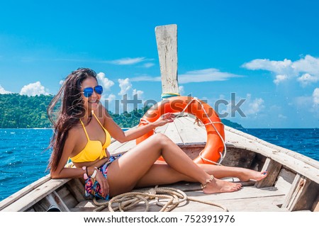 Happy traveler asian woman in bikini enjoying and relaxing with life buoy on wooden boat, Andaman sea, Surin island, Travel in Thailand, Summer holiday and vacation trip