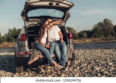 Happy Traveler Couple On Picnic Into The Sunset With SUV Car