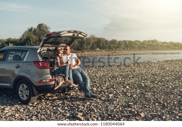Happy Traveler Couple on Picnic into the Sunset with\
SUV Car