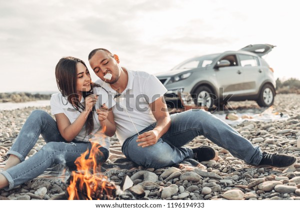 Happy Traveler Couple on Picnic into the Sunset with
SUV Car