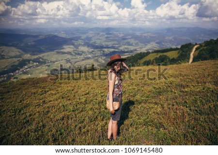 happy traveler hipster girl in hat, walking in sunny mountains. summer vacation. space for text. happy atmospheric moment. woman traveling. travel and wanderlust concept