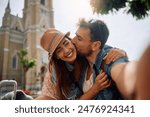Happy traveler kissing his girlfriend while taking selfie in the city. 