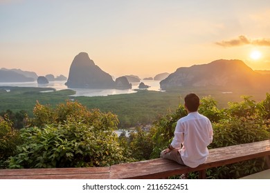 Happy traveler man enjoy Phang Nga bay view point, alone Tourist sitting and relaxing at Samet Nang She, near Phuket in Southern Thailand. Southeast Asia travel, trip and summer vacation concept