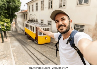 Happy traveler man enjoying summer vacation in Portugal. Smiling tourist taking selfie with yellow Lisbon tran during Europe holidays. - Powered by Shutterstock