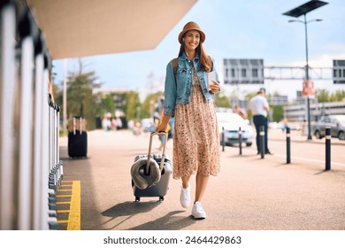 Happy traveler pulling her suitcase while walking at the station. Copy space. - Powered by Shutterstock