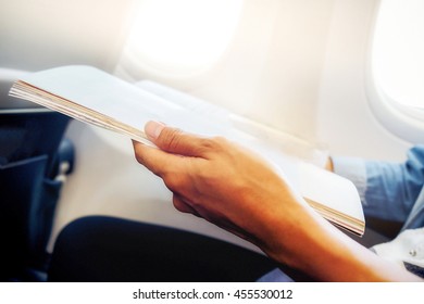 Happy Traveler Reading A Magazine In An Airplane.Vintage Tone Retro Filter Effect,soft Focus,low Light.