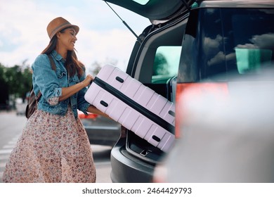 Happy traveler taking her suitcase out of car trunk on parking lot. Copy space.  - Powered by Shutterstock