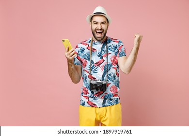 Happy Traveler Tourist Man In Summer Clothes, Hat Using Mobile Phone Typing Sms Message Doing Winner Gesture Isolated On Pink Background. Passenger Traveling On Weekends. Air Flight Journey Concept