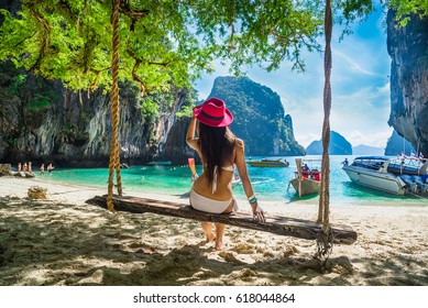 Happy traveler woman in bikini relaxing on swing under tree looking destinations sea beach, Lao Lading island, Andaman sea, Krabi, Phuket, Travel Thailand, Tourist Asia, Summer holiday vacation trip