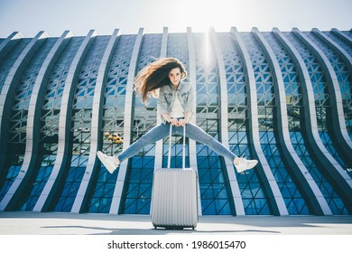 Happy traveler woman jumps near airport.