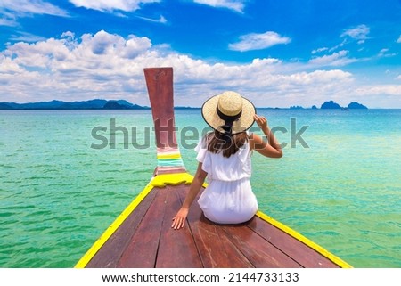 Happy traveler woman relaxing on boat near tropical island in Thailand