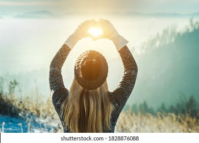 Happy traveler woman tourist stay on mountain top and making of love heart by hands in sunny frozen winter day. - Powered by Shutterstock