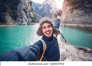 Happy traveller man takes a selfie photo on a lake at the mountain 