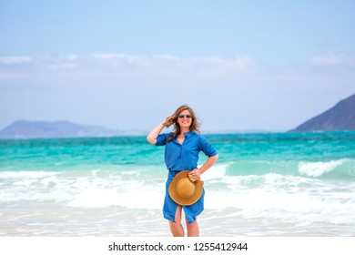 Happy traveller woman in blue dress enjoys her tropical beach vacation