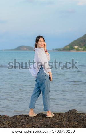 Happy traveller woman in white dress enjoys her tropical beach vacation.